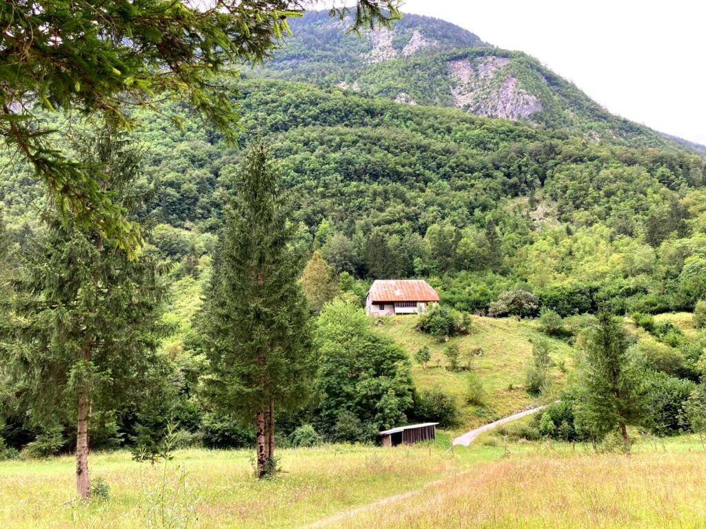 Bauernhäuser und bewaldete Berghänge am Soča-Trail.