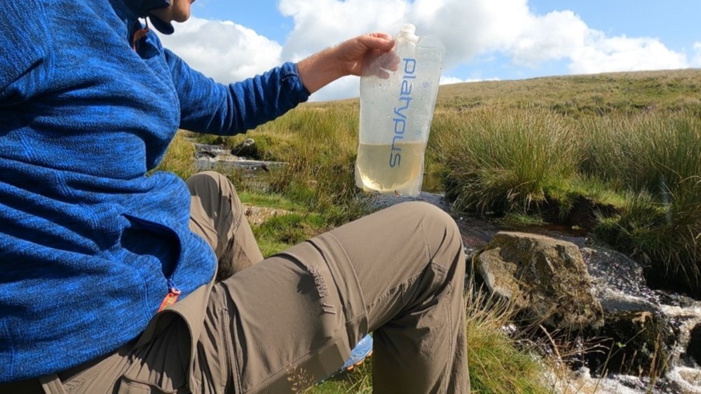 Wasserfiltern an einem Dartmoor Bach.