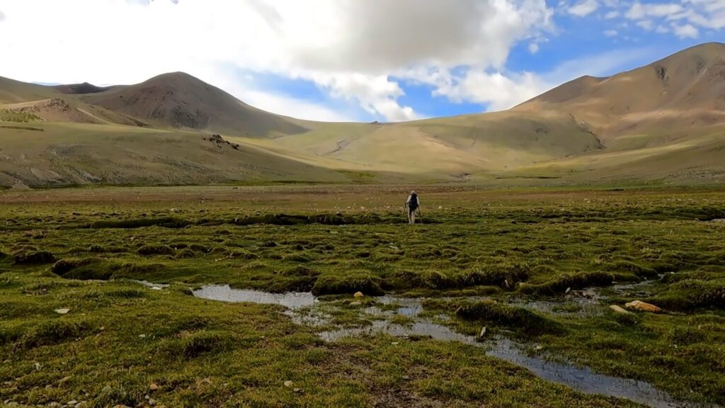 Wanderer in einsamer Gebirgslandschaft vor Pass.