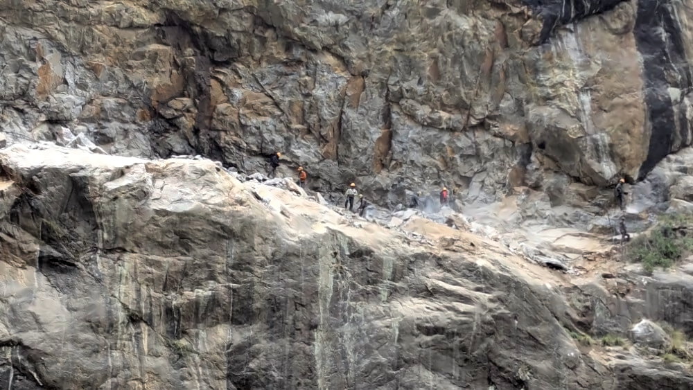 Bauarbeiter in einer Steilwand hinter Jagat.