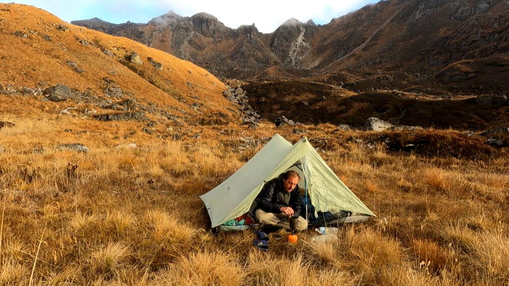 Wanderer sitzt im Zelt und kocht beim Camping im Himalaya.