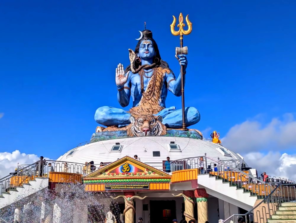 Shiva Statue in Pumdikot mit blauem Himmel und weißen Himalaya-Bergen im Hintergrund.