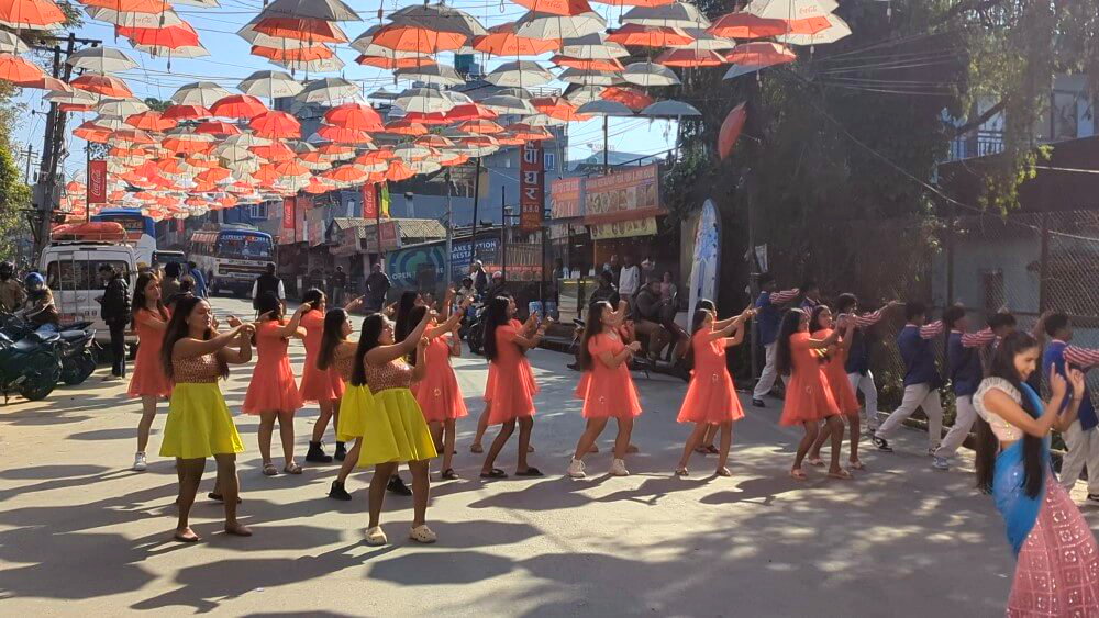 Tanzende Nepali Frauen unter Regenschirmen im Zentrum von Lakeside.